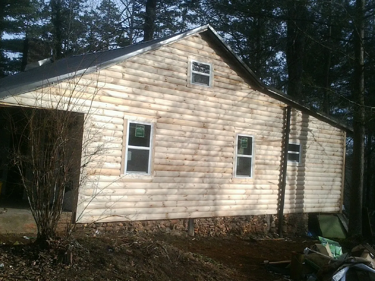 New log siding and dark metal roofing on a gable end in Allen