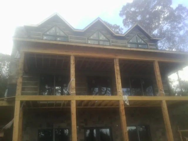 Dormers and porch framing on a large log home under construction — Roof Coating work by our crew in Allen