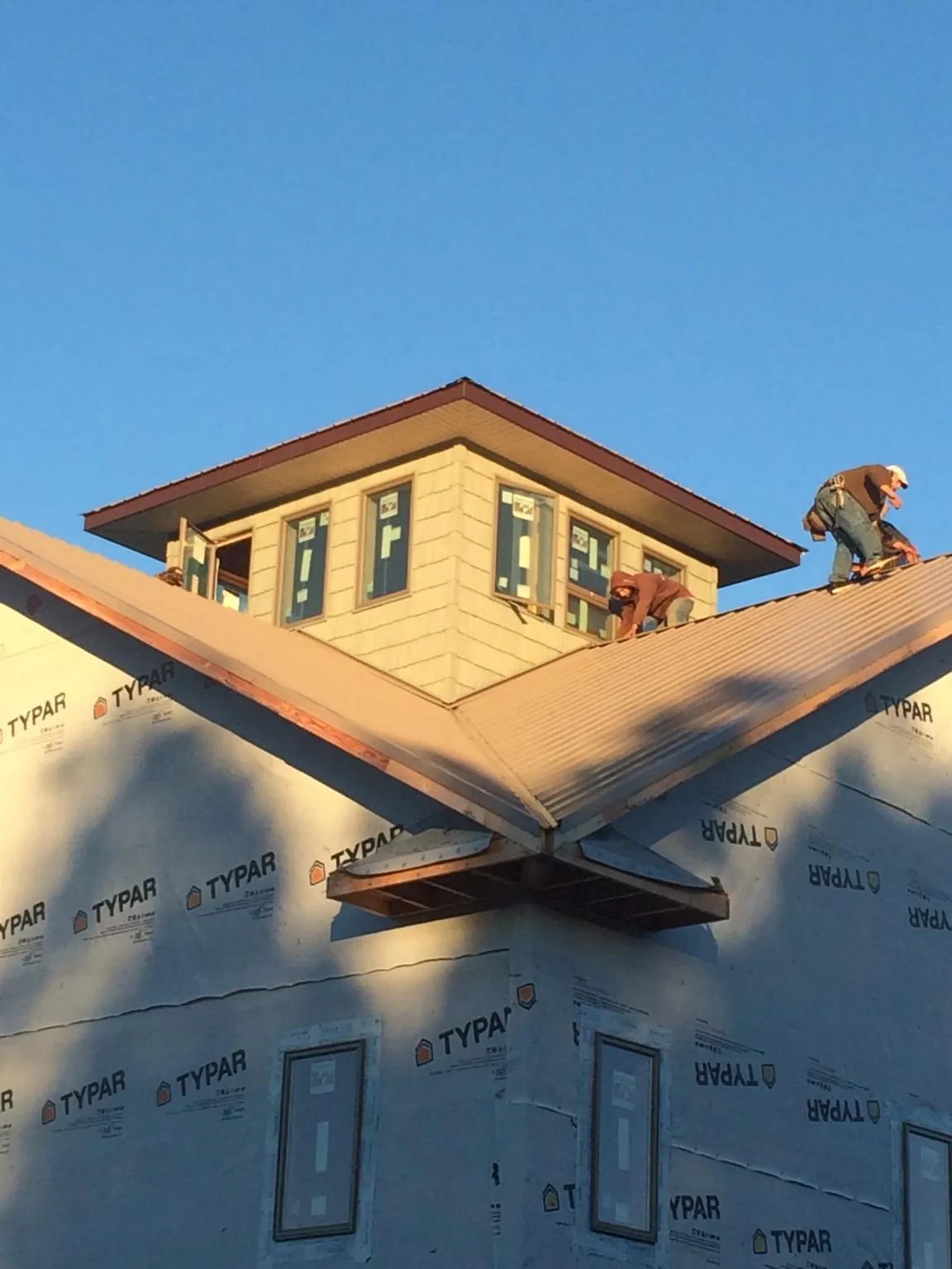 Roofers working around a rooftop cupola on a new metal roof at sunset — Roof Waterproofing in Allen by Roofing Brothers
